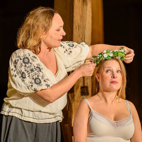 Eine Frau setzt einer anderen Frau auf dem Tuppenhof in Kaarst einen Blumenkranz auf den Kopf.