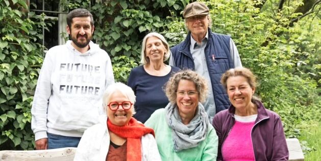 Gruppe von sechs Personen posiert lächelnd im Tuppenhof, Kaarst, umgeben von grüner Natur.