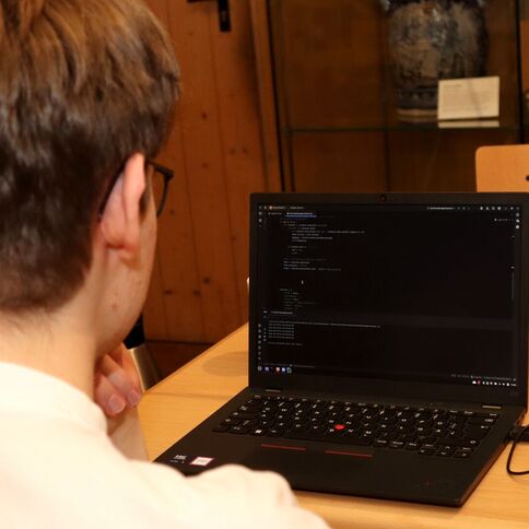 Ein junger Mann arbeitet konzentriert am Laptop im Tuppenhof in Kaarst, umgeben von Getränken und Snacks.