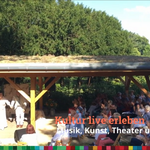 Im Tuppenhof in Kaarst genießen Zuschauer eine lebendige Kulturaufführung unter einem überdachten Platz.