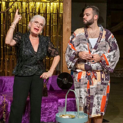 Eine Frau spricht leidenschaftlich auf der Bühne, während ein Mann in einem Kimono neben ihr steht.