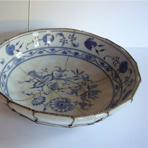 Eine gesprungene Porzellanschale ist auf der Unterseite mit Draht stabilisiert worden. © Museum Tuppenhof