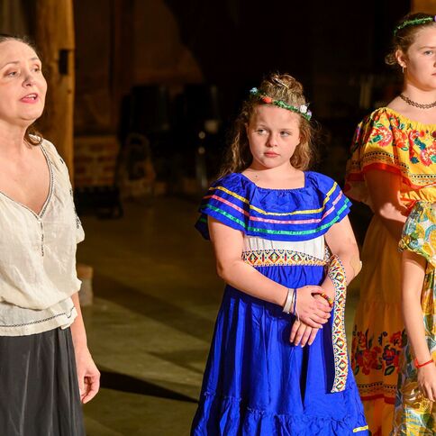 Eine Frau und drei Mädchen in bunten Kleidern stehen während einer Aufführung im Tuppenhof in Kaarst auf der Bühne.