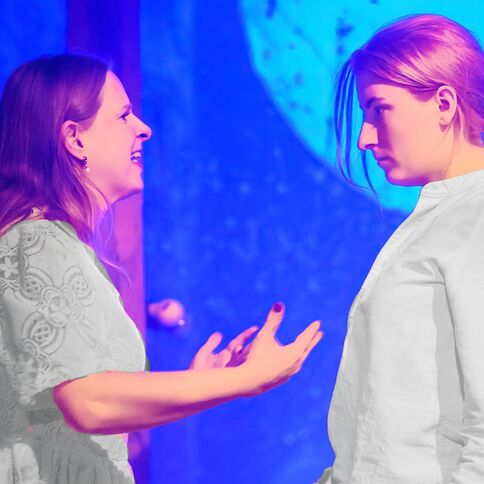 Zwei Frauen stehen sich auf einer Bühne gegenüber und diskutieren lebhaft, möglicherweise bei einer Aufführung im Tuppenhof Kaarst.