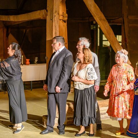 Eine Gruppe von Menschen in traditioneller Kleidung steht in einer Scheune des Tuppenhofs in Kaarst bei einer Veranstaltung.