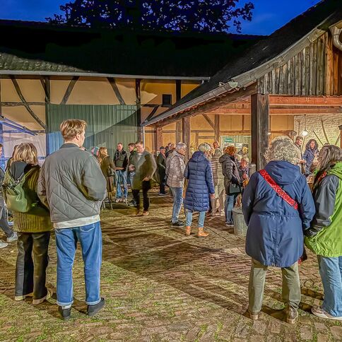 Eine Gruppe von Menschen unterhält sich auf dem stimmungsvoll beleuchteten Hof des Tuppenhofs in Kaarst.