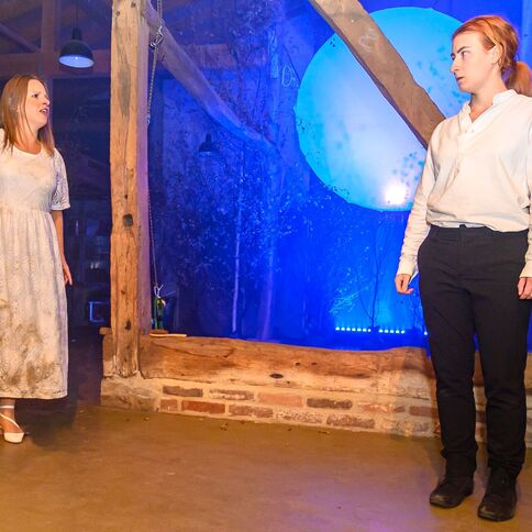 Zwei Frauen stehen in einem rustikalen Raum auf dem Tuppenhof in Kaarst, während sie intensiv miteinander sprechen.