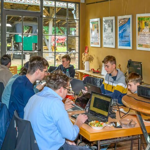 Mehrere Personen arbeiten konzentriert an Laptops im Tuppenhof in Kaarst, während Sonnenlicht durch die Fenster fällt.