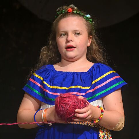 Ein Mädchen in einem bunten Kleid hält ein Wollknäuel in der Hand, möglicherweise bei einer Veranstaltung am Tuppenhof, Kaarst.