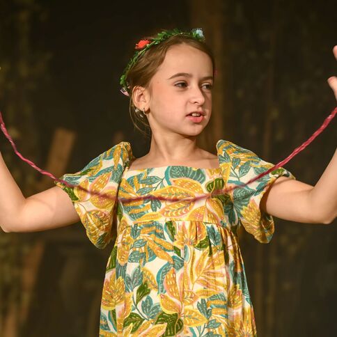 Ein Mädchen in einem bunten Kleid spielt mit einem roten Faden bei einer Veranstaltung im Tuppenhof Kaarst.