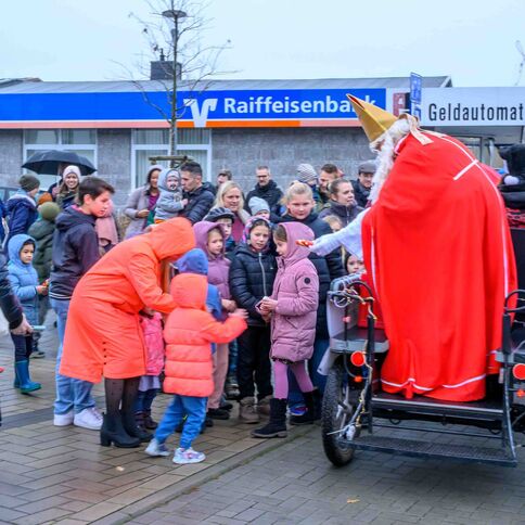 Ein als Nikolaus verkleideter Mann verteilt in Kaarst Süßigkeiten an Kinder vor einer Raiffeisenbank.