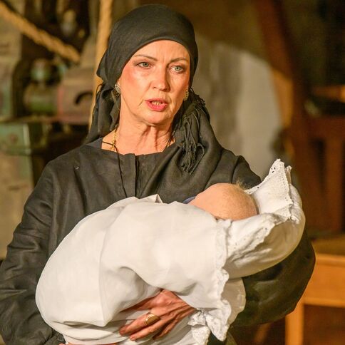 Eine Frau in traditioneller Kleidung hält ein Baby im Tuppenhof in Kaarst.