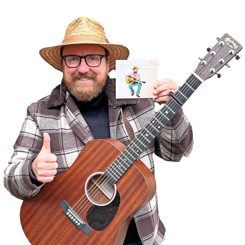 Ein Mann mit Strohhut hält eine Akustikgitarre und eine CD, während er lächelnd den Daumen hebt.