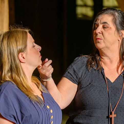 Zwei Frauen stehen im Tuppenhof in Kaarst, während eine der Frauen der anderen zärtlich das Gesicht berührt.