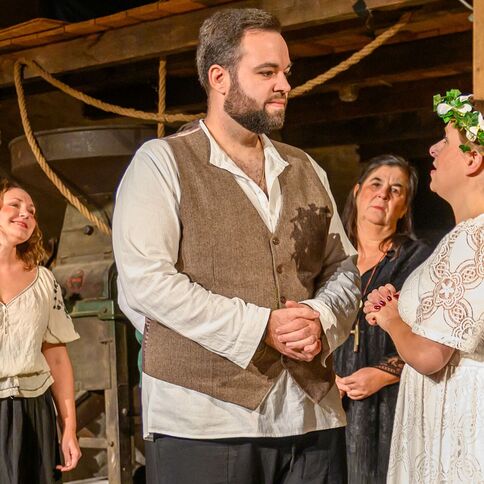 In einem rustikalen Raum des Tuppenhofs in Kaarst stehen vier Personen während einer emotionalen Theaterszene zusammen.