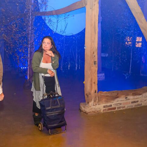 Eine Frau mit einem Einkaufstrolley und ein Mann stehen im stimmungsvoll beleuchteten Innenbereich des Tuppenhofs in Kaarst.