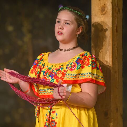 Ein Mädchen in einem bunten Kleid singt auf einer Bühne am Tuppenhof in Kaarst.