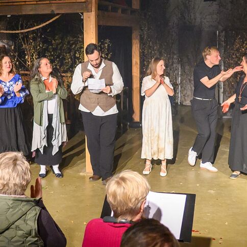 Eine Theatergruppe verbeugt sich lächelnd nach einer Aufführung im Tuppenhof in Kaarst vor dem applaudierenden Publikum.