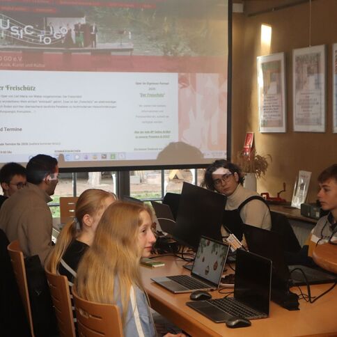 Jugendliche arbeiten in Kaarst am Tuppenhof gemeinsam an Laptops, während eine Präsentation an der Wand projiziert wird.