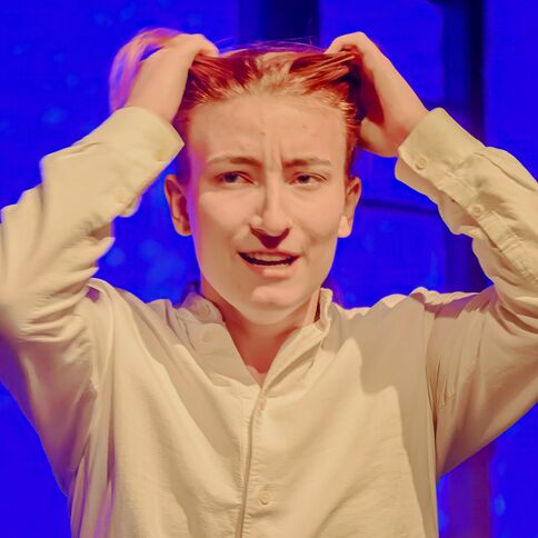 Eine Person in weißem Hemd hält sich gestresst den Kopf vor einem blauen Hintergrund im Tuppenhof Kaarst.