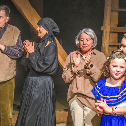 Eine bunt gekleidete Gruppe applaudiert lächelnd bei einer Veranstaltung im Tuppenhof in Kaarst.