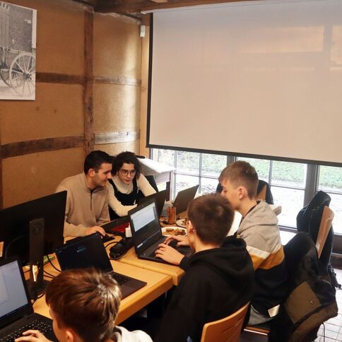 Mehrere Personen arbeiten konzentriert an Laptops in einem gemütlichen Raum mit Holzverkleidung im Tuppenhof Kaarst.