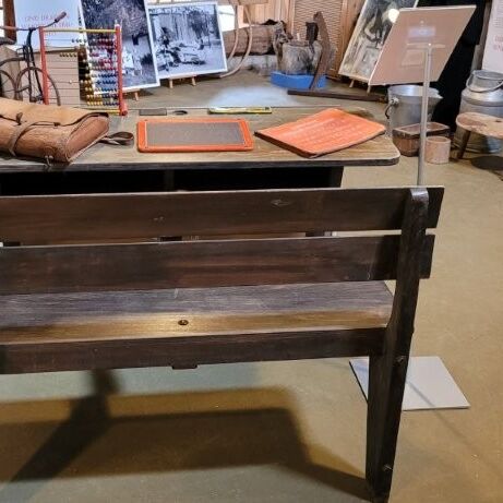 Eine Holzbank steht vor einem Tisch mit historischen Objekten im Tuppenhof in Kaarst. | © Tuppenhof