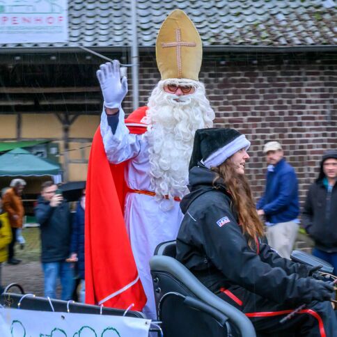Ein als Nikolaus verkleideter Mann winkt auf einem Fest in Tuppenhof, Kaarst, während er von einer Frau auf einer Kutsche begleitet wird.