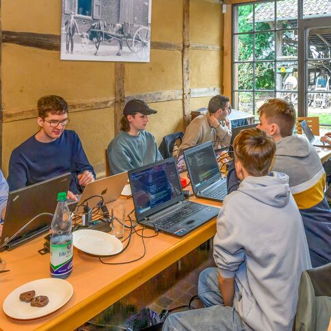Eine Gruppe junger Menschen arbeitet konzentriert an Laptops im gemütlichen Ambiente des Tuppenhofs in Kaarst.