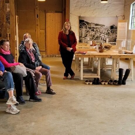 Eine Gruppe von Personen sitzt im Tuppenhof Kaarst, während eine Präsentation im Hintergrund stattfindet.