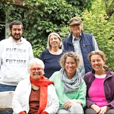 Gruppe von sechs Personen posiert lächelnd im Tuppenhof, Kaarst, umgeben von grüner Natur.
