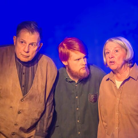 Drei Personen stehen auf einer Bühne im Tuppenhof in Kaarst und sind in ein Gespräch vertieft.