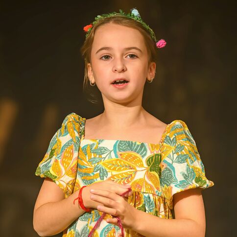 Ein Mädchen in einem bunten Kleid singt mit ausdrucksstarker Mimik bei einer Veranstaltung im Tuppenhof Kaarst.