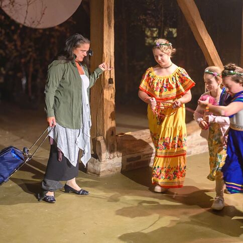 Eine Frau mit einem Einkaufswagen beobachtet drei Kinder in bunten Kleidern beim Spielen im Tuppenhof in Kaarst.