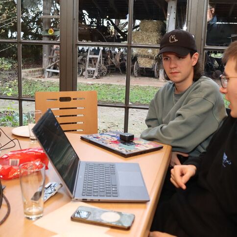 Zwei junge Männer arbeiten konzentriert an einem Laptop in einem Raum mit Blick auf den Tuppenhof in Kaarst.