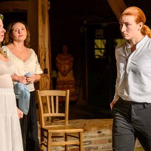 Drei Personen stehen in einem rustikalen Raum auf dem Tuppenhof in Kaarst, wobei eine ernste Diskussion im Gange ist.