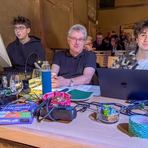 Drei Personen arbeiten konzentriert an Computern und Technik im Tuppenhof Kaarst, umgeben von Getränken und Süßigkeiten.