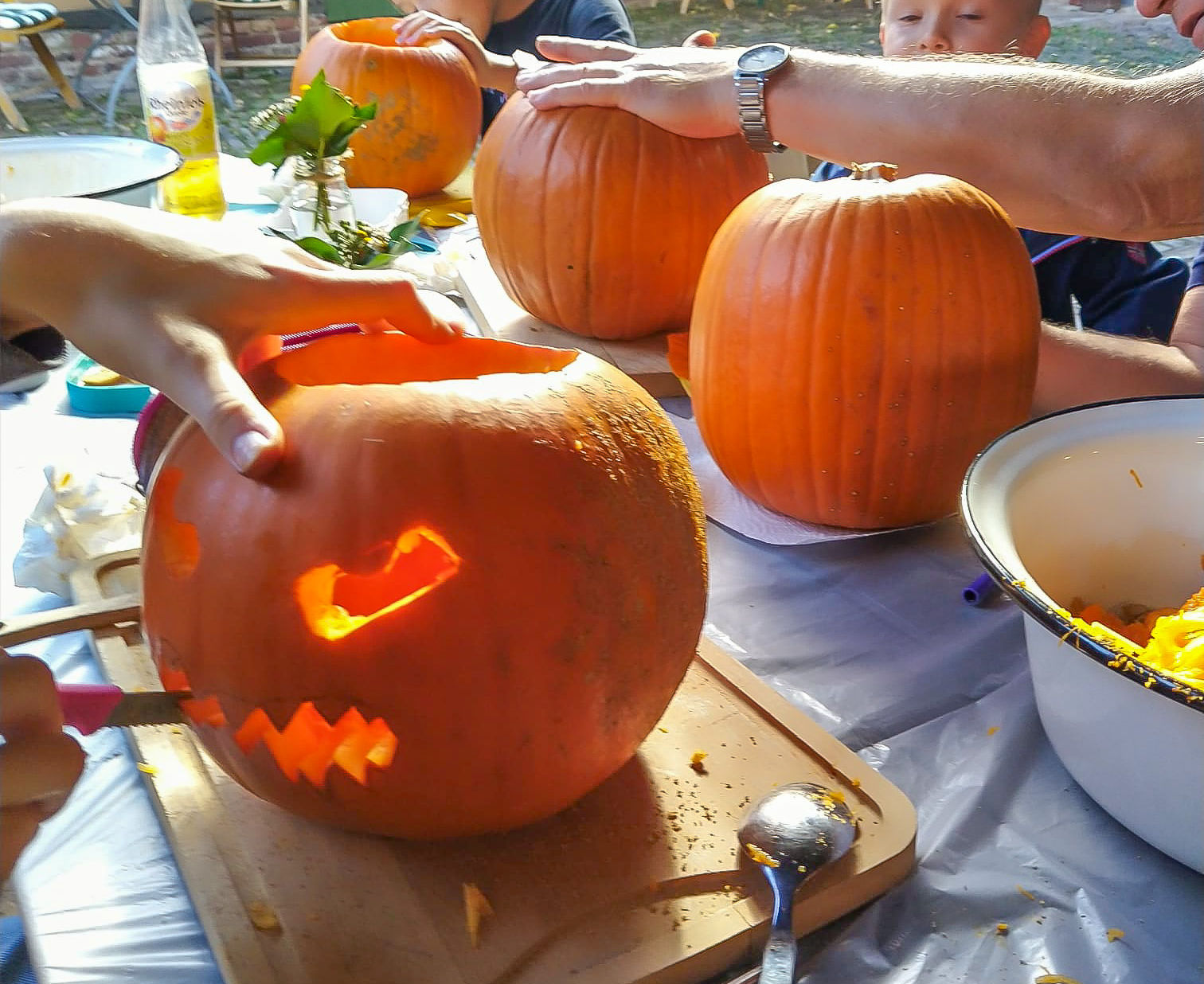 Familienmitglieder schnitzen gemeinsam leuchtende Kürbisse bei einem fröhlichen Fest im Tuppenhof, Kaarst.