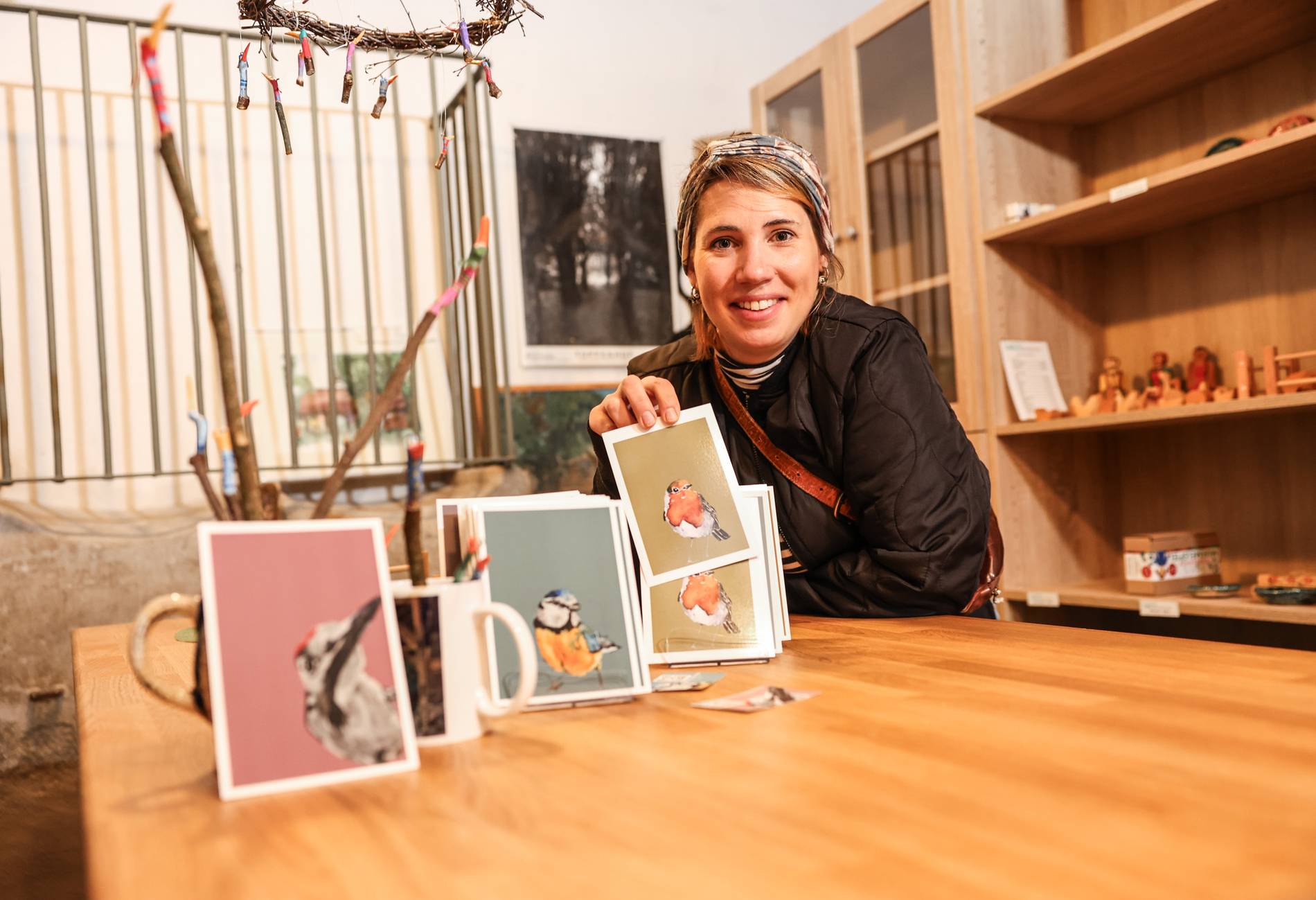 Eine lächelnde Frau präsentiert Kunstkarten im Tuppenhof in Kaarst auf einem Holztablett.